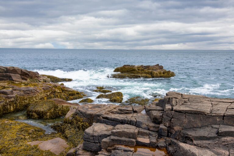 Scenic view of the rocky coastline at Bar Harbor with crashing waves and cloudy sky.